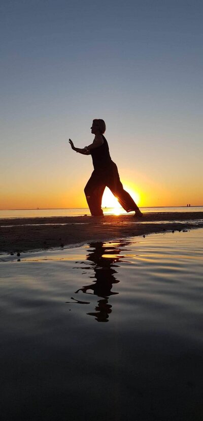 Ulla Kronel, Qi Gong ved havet med solen som baggrund og spejling i vandet.